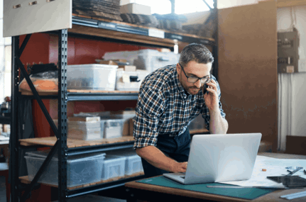 Ondernemer telefoneert en kijkt op laptop