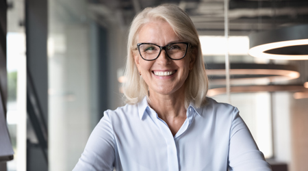 Een oudere lachende en vitale medewerkster op kantoor