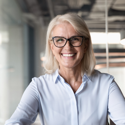 Een oudere lachende en vitale medewerkster op kantoor
