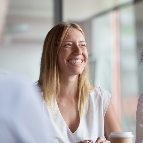 Een lachende vrouw op kantoor met haar collega's